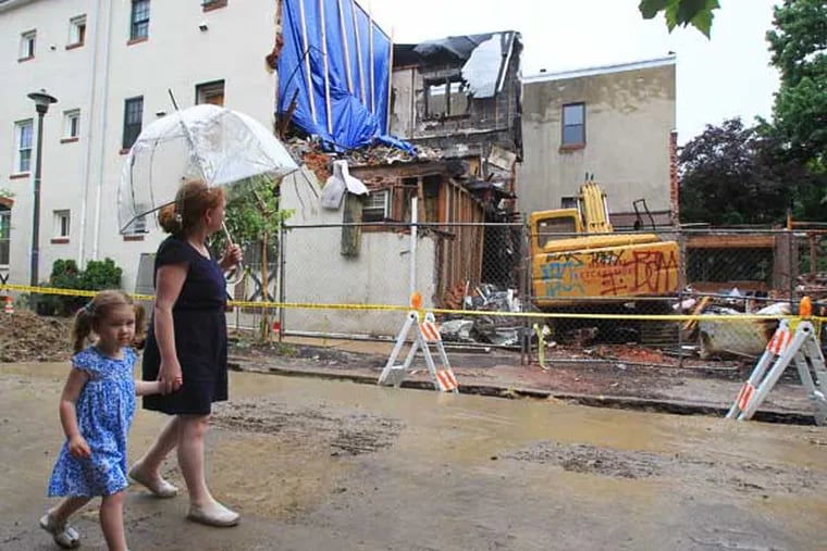 In early May, the residents of the 2300 block of Naudain Street in Philadelphia were awaken by shrieking carbon monoxide detectors. Officials from the Fire Department and Philadelphia Gas Works responded and measured off-the-charts levels of the poisonous gas. A few minutes later, a rowhouse exploded, taking down the neighboring structures as well.  Laura Brennan and her daughter, Sara Brennan, 3, walk by the ruins on June 19, 2014.   ( CHARLES FOX / Staff Photographer )