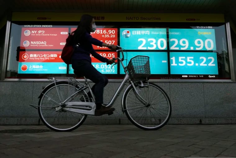 A woman rides a bicycle past an electronic stock board showing Japan's Nikkei 225 index at a securities firm in Tokyo on Friday.