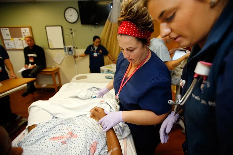 Melissa Ems (center) and Noelle Dominic treat a medical simulation
as the real thing as they tend to an actor showing signs of bleeding
at the Hospital of the University of Pennsylvania.