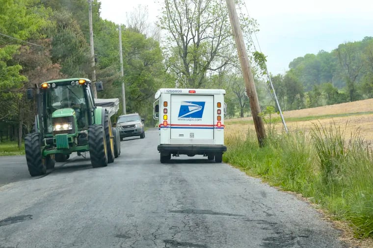Chester Springs Post Office letter carrier Tim Viola drives past farm equipment on his route in rural Chester County.