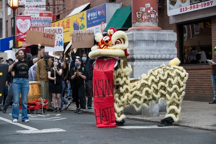 During a rally to support and protect Asian Americans, a lion dancer holds up a sign reading “Stop Asian Hate” after a dance on 10th Street in Chinatown.