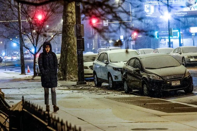Julia Mockus walks along the 1300 block of South Broad Street as it started to snow Monday.