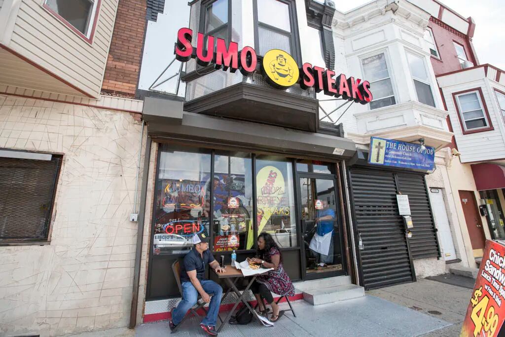 Sumo Steaks co-founder Billy Creagh and the 2800 block of North 22d ambassador Thera Martin Milling sit outside Sumo Steaks. ( Colin Kerrigan / Philly.com )