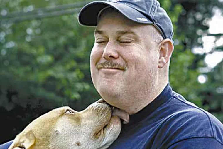 Patrick O'Donnell of Levittown gets a smooch from his dog Otis. O'Donnell is a postal worker who was injured in the anthrax attacks in 2001. (Akira Suwa / Inquirer)