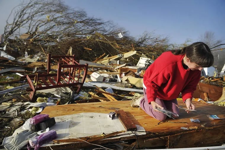 Diana Davis sifts through rubble for photos after a tornado tore through her father-in-law's house in Lutts, Tenn.