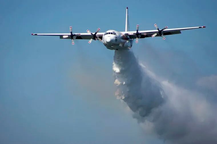 In this undated photo released from the Rural Fire Service, a C-130 Hercules plane called "Thor" drops water during a flight in Australia. Officials in Australia on Thursday, Jan. 23, 2020, searched for a water tanker plane feared to have crashed while fighting wildfires.