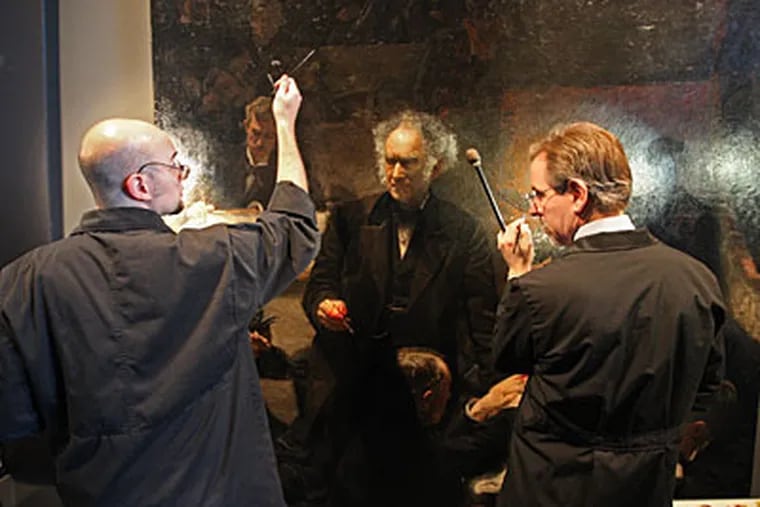 Allen Kosanovich and Mark S. Tucker (right) work on Thomas Eakins’ “The Gross Clinic,” which temporarily shares a room at the Philadelphia Museum of Art’s Perelman Building with a Rembrandt. (MICHAEL BRYANT / Staff Photographer)