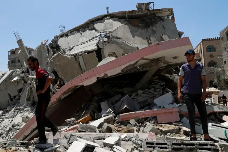 People walk amid the rubble of a destroyed residential building, which was hit by Israeli airstrikes, in Gaza City on Wednesday.