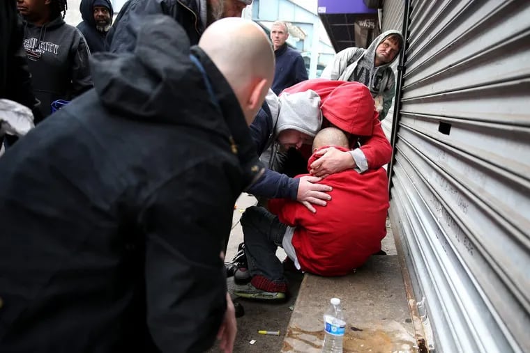 Friends hug an unidentified man (bottom right) after he was revived from a heroin overdose along Kensington Avenue in Philadelphia in 2017.