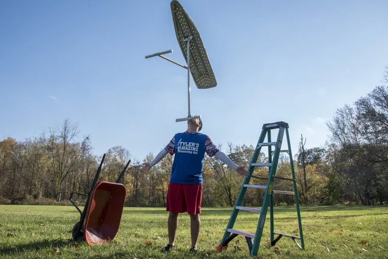 Tyler Scheuer, 23, from Newtown. Bucks County, balances an ironing board on his chin in Tyler State Park, while a wheelbarrow and a 10-foot ladder await their turn on his face.