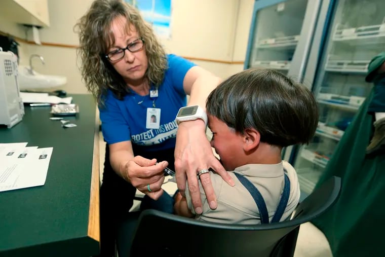 In this Friday, May 17, 2019 photo, Starr Roden, left, a registered nurse and immunization outreach coordinator with the Knox County Health Department, administers a vaccination to Jonathan Detweiler, 6, at the facility in Mount Vernon, Ohio. (AP Photo/Paul Vernon)