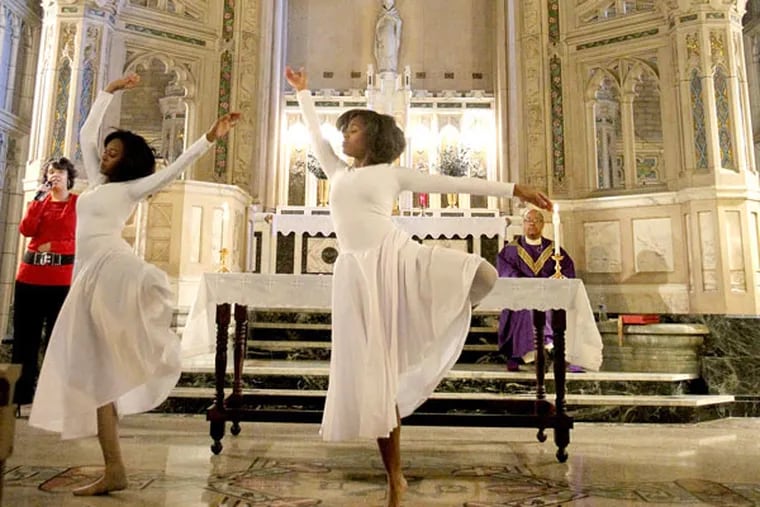Sisters Taylor (left) and Amber Felder dance at the Mass on Sunday. (Charles Fox / Staff Photographer)