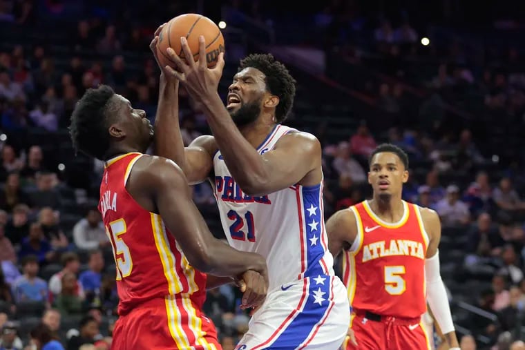 Joel Embiid of the Sixers collides with Clint Capela of the Hawks during the first half of their preseason game at the Wells Fargo Center. Embiid was called for an offensive foul.