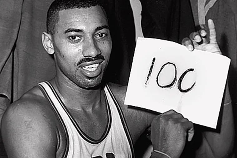 Wilt Chamberlain of the Philadelphia Warriors holds a sign reading "100." (AP File Photo/Paul Vathis)