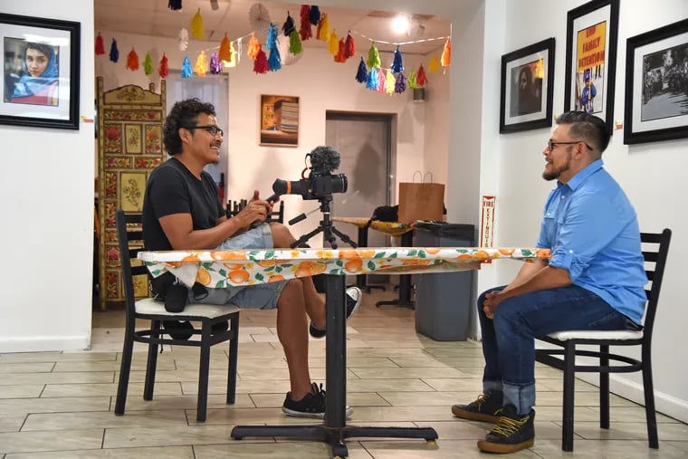 Antonio Arroniz, left, interviews photographer José Mazariegos, right, at the opening reception for an exhibit of his work - The Beautiful (Un)Ordinary - at Barbacoa August 12, 2019. Arroniz is a video producer for PhillyCAM Latino presents: Atrévete.