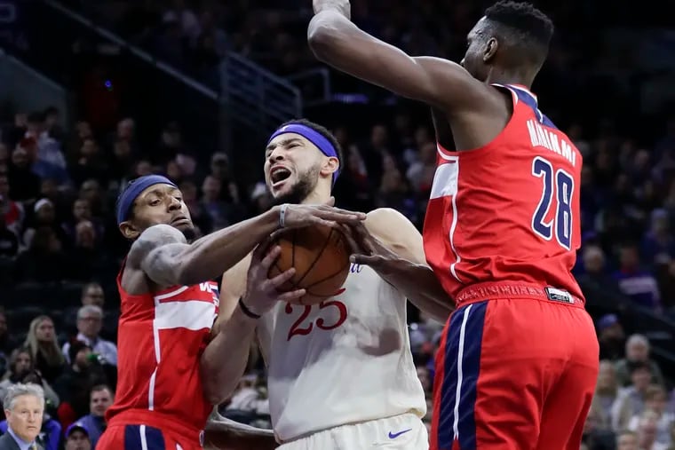 Sixers guard Ben Simmons gets fouled driving to the basket against Washington Wizards guard Bradley Beal (left) and center Ian Mahinmi during the first quarter of Saturday's game at the Wells Fargo Center.