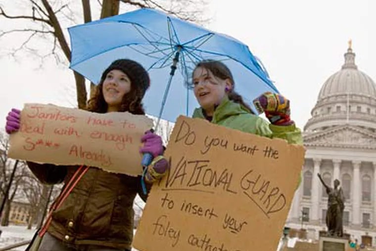 Jane Moran, left, 14, and Emma Rankin-Utevsky, 14, protest outside of the State Capitol in Madison, Wisconsin on Sunday. Opponents to the governor's bill to eliminate collective bargaining rights for many state workers are on their sixth day of protesting. (AP Photo/Andy Manis)
