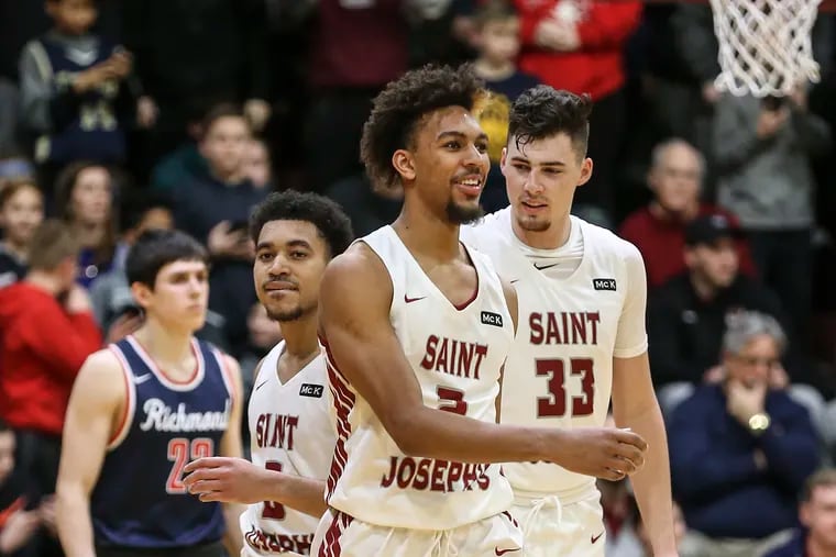 St. Joseph's Charlie Brown Jr. smiles with teammates Jared Bynum and Taylor Funk as they walk by Richmond's Andre Gustavson on his way to shot his foul shot with seconds left din the game at The Michael J. Hagan Arena, Wednesday, January 23, 2019. St. Joseph's beat Richmond 74-70. STEVEN M. FALK  /  Staff Photographer