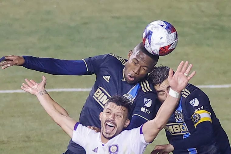 Union midfielder Andrés Perea heads the soccer ball with teammate midfielder Alejandro Bedoya against Orlando City midfielder Felipe Martins.