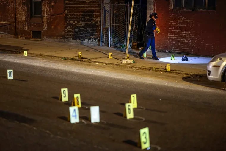 A crime-scene officer places makers on evidence on the 3900 block of Poplar Street in West Philadelphia where an 18-year-old man was fatally shot around 7:30 p.m., Tuesday, May 25, 2021.  A 15-year-old boy was fatally shot about a half-hour later in North Philadelphia.