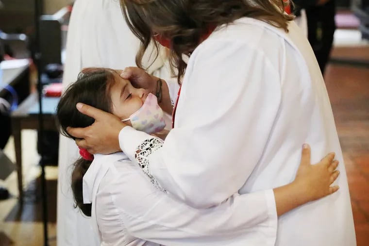Rev. Yesenia "Jessie" Alejandro (right) hugs her granddaughter Isabella Lazarde, 7, after her ordination ceremony at St. John's Episcopal Church in Norristown, Pa., on Saturday, Oct. 10, 2020. Alejandro is the first Latina ordained priest in the Episcopal Diocese of Pennsylvania.