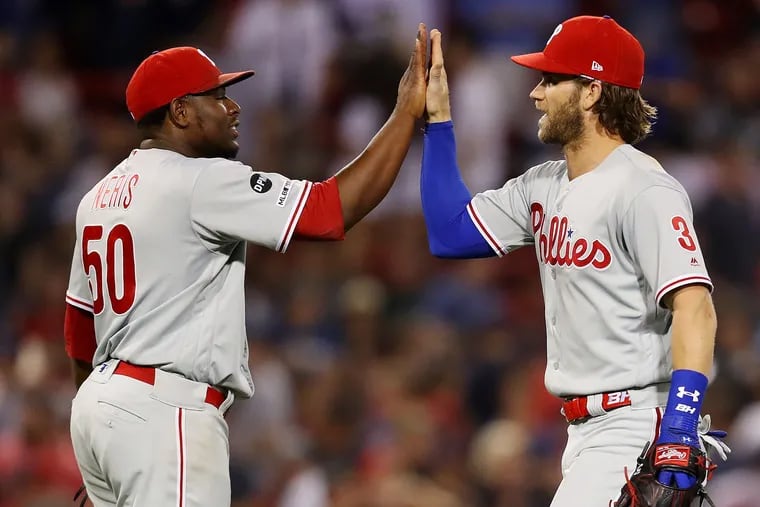 The Phillies' Bryce Harper (3) and Hector Neris (50) celebrate after defeating the Boston Red Sox, 3-2, at Fenway Park on Tuesday.