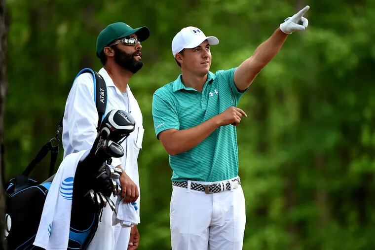 Jordan Spieth explains his shot from the rough along the 11th
fairway to his caddie, Michael Greller, during the first round of the Masters.