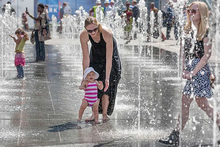 With a guiding hand from mother Melissa, Avery Vadnais navigates the fountains on Thursday at the newly opened Dilworth Park. One-third of the park is unfinished, due to be completed by Thanksgiving.