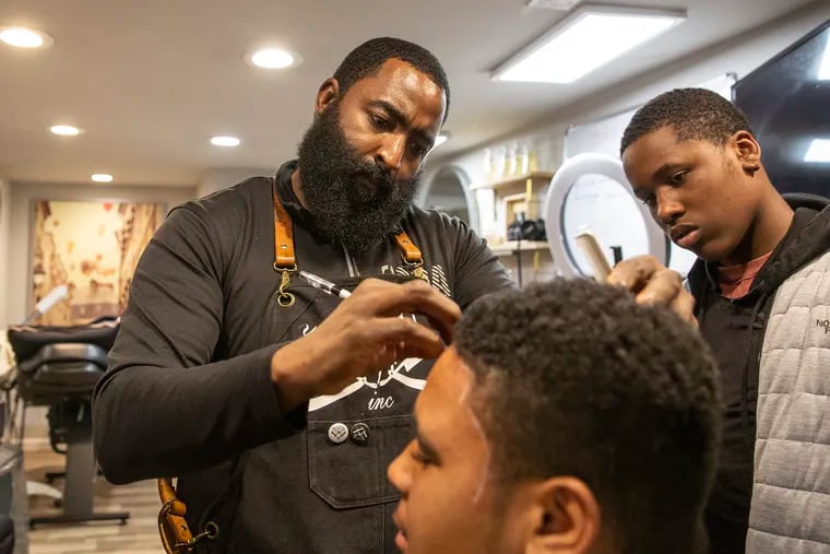 Prentice Michael Boone helps teach his young students the art of being a barber at his Junior Academy course on a Friday evening in 2018.