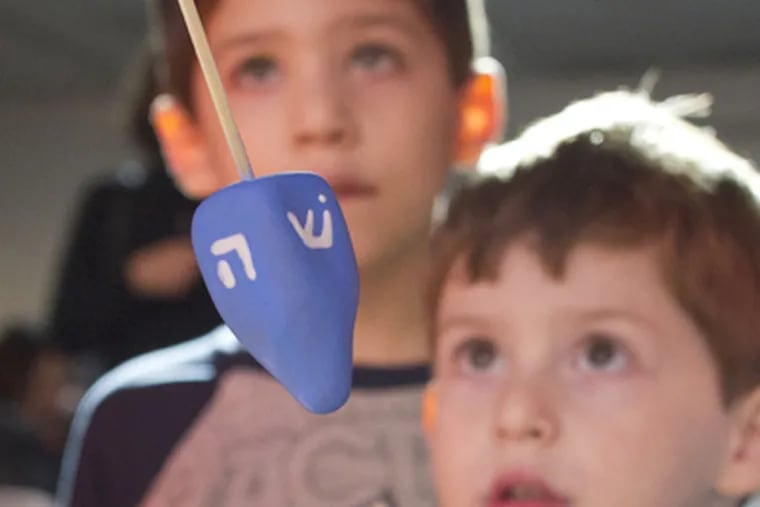 Brothers Bennett, 6, and Jonah Kutikov, 4, watch the dreidel-making demonstration put on by the Clay Studio at the National Museum of American Jewish History. (David M Warren / Staff Photographer)
