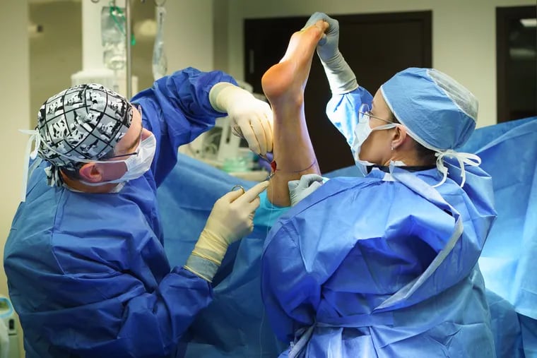 Orthopedic surgeon Steven Raikin (left) and Dr. Alexis Williams, an orthopedic surgery resident, begin 50-year-old Brian Adams' surgery for fallen arches.