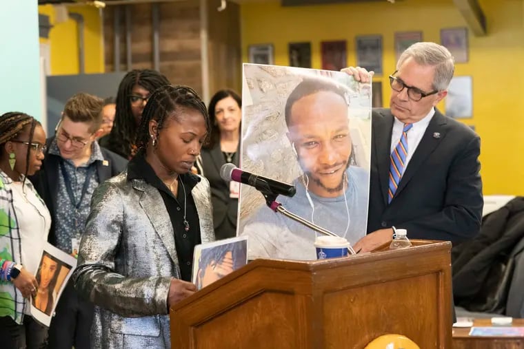 Markiya Jackson, front left, holds a photo of  sibling Mar'Quis "MJ" Jackson, while speaking during a news conference with Larry Krasner, back right, at GALAEI, in Philadelphia, Wednesday.