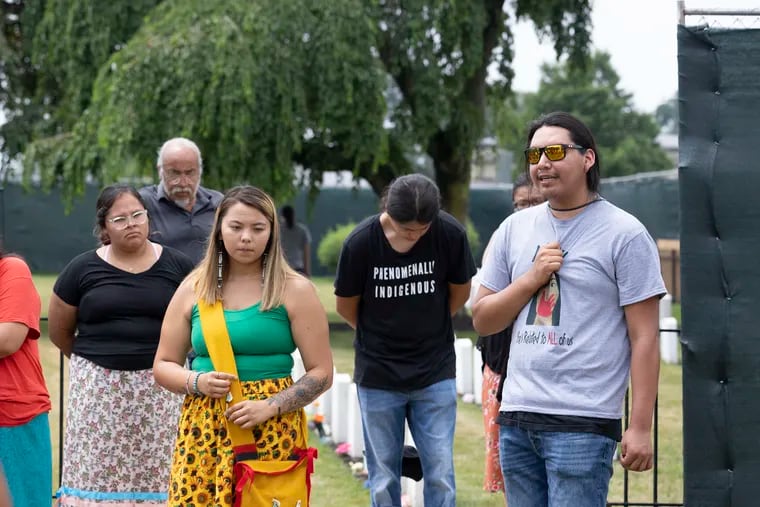 The Sicangu Youth Council initiated the repatriation process at the Carlisle Indian Industrial School. The remains of nine students from the Rosebud Sioux will be returned to their homeland.  Christopher Eagle Bear, right, one of the youth council members, clutches his chest as he sings as the group gathers outside the cemetery at the Carlisle Barracks on July 13, 2021.