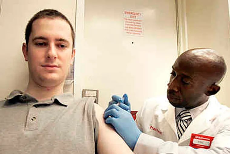 In this October photo, David Yoslov, 23, gets a flu shot from pharmacist Eric Reid at the CVS at 19th and Chestnut. (David Swanson/File)