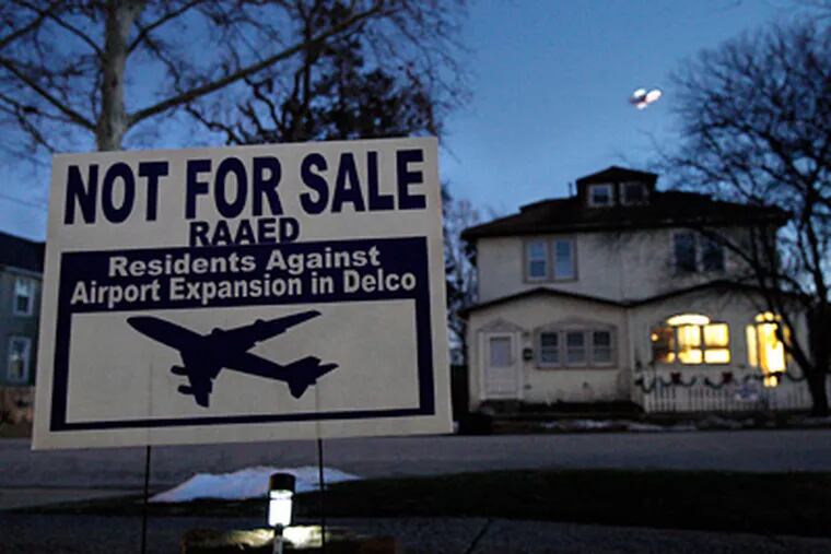 A sign in Tinicum Township , as an airplane takes off in the distance. &quot;We're not there just yet,&quot; said the airport's CEO. (Elizabeth Robertson / Staff Photographer)