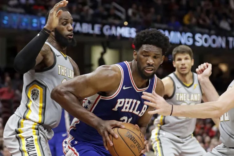 The Sixers&#039; Joel Embiid (center) dribbles against the Cavaliers&#039; LeBron James (left) on Thursday.