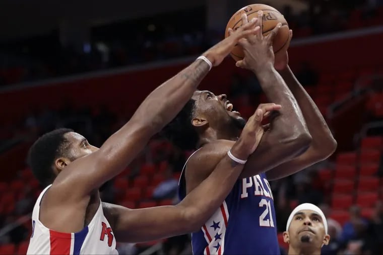 Joel Embiid (21) shoots as Pistons center Andre Drummond reaches in during the second half Monday night.