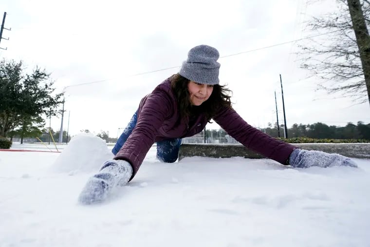 Cristina Lucero gathers snow while trying to build a snowman in Houston.