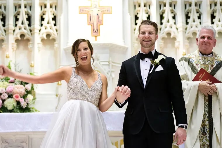 Bride Elise DelCasale's and her groom Bill Viscuso jubilate under the watchful eye of Monsignor Paul Kennedy at the end of their ceremony at St. John the Evangelist.