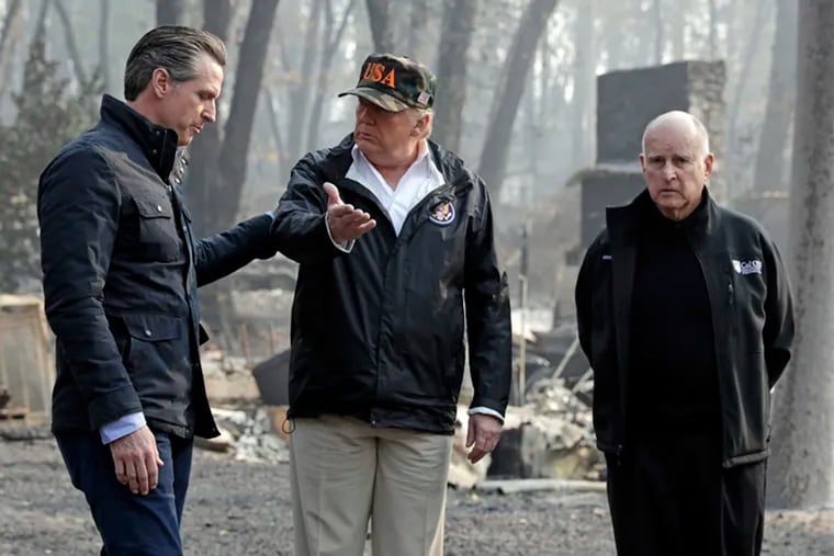 FILE - In this Nov. 17, 2018 file photo, President Donald Trump talks with Gov.-elect Gavin Newsom, left, as California Gov. Jerry Brown listens during a visit to a neighborhood impacted by the Camp wildfire in Paradise, Calif. President Donald Trump is threatening to withhold Federal Emergency Management Agency money to help California cope with wildfires if the state doesn't improve its forest management practices. Trump tweeted Wednesday, Jan. 9, 2019, that California gets billions of dollars for fires that could have been prevented with better management. (AP Photo/Evan Vucci, File)