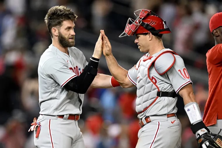 Bryce Harper congratulates catcher J.T. Realmuto after the Phillies' 8-7 victory in the second game of a doubleheader Friday night in Washington.