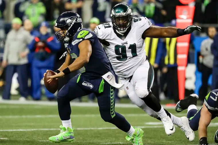 Seattle Seahawks quarterback Russell Wilson runs past Eagles defensive tackle Fletcher Cox in the fourth-quarter on Sunday, December 3, 2017 at CenturyLink Field in Seattle.  YONG KIM / Staff Photographer