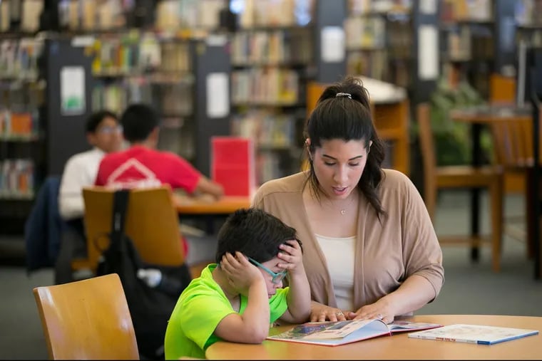 Cristine Gonzalez, right, does reading homework with her six-year-old son Dean Pagan, left, at their local library branch, Northeast Philadelphia, Wednesday, May 2, 2018. Dean was severely lead poisoned at Comly Elementary School. 