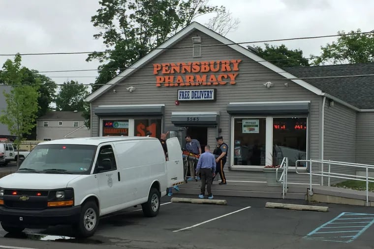 Bucks County coroner’s staffers remove the body of the alleged robber from the pharmacy. The business opened in December. A bicycle shop had been at the location before that.