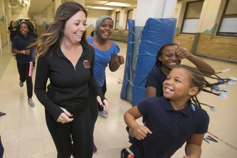 Mitchell Elementary Principal Stephanie Andrewlevich runs with students in the gym on a rainy day.