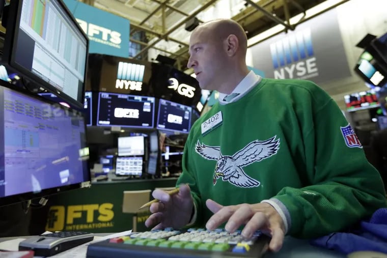 Specialist Jay Woods wears a vintage Philadelphia Eagles sweater as he work at his post on the floor of the New York Stock Exchange on Monday. Stock markets around the world took another pummeling Monday as investors continued to fret over rising U.S. bond yields.