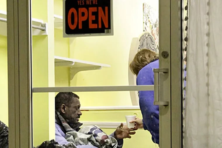 Volunteer Joan McConnon brings a cup of coffee to Rinaldo Sanchez at the Hub of Hope, an outreach office for the homeless in a former hair salon at Suburban Station. (Elizabeth Robertson/Staff)