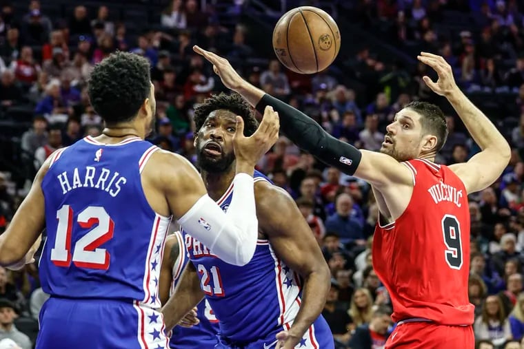 The Sixers’ Tobias Harris and Joel Embiid watch a loose ball with the Bulls’ Nikola Vucevic during the first quarter on Monday.
