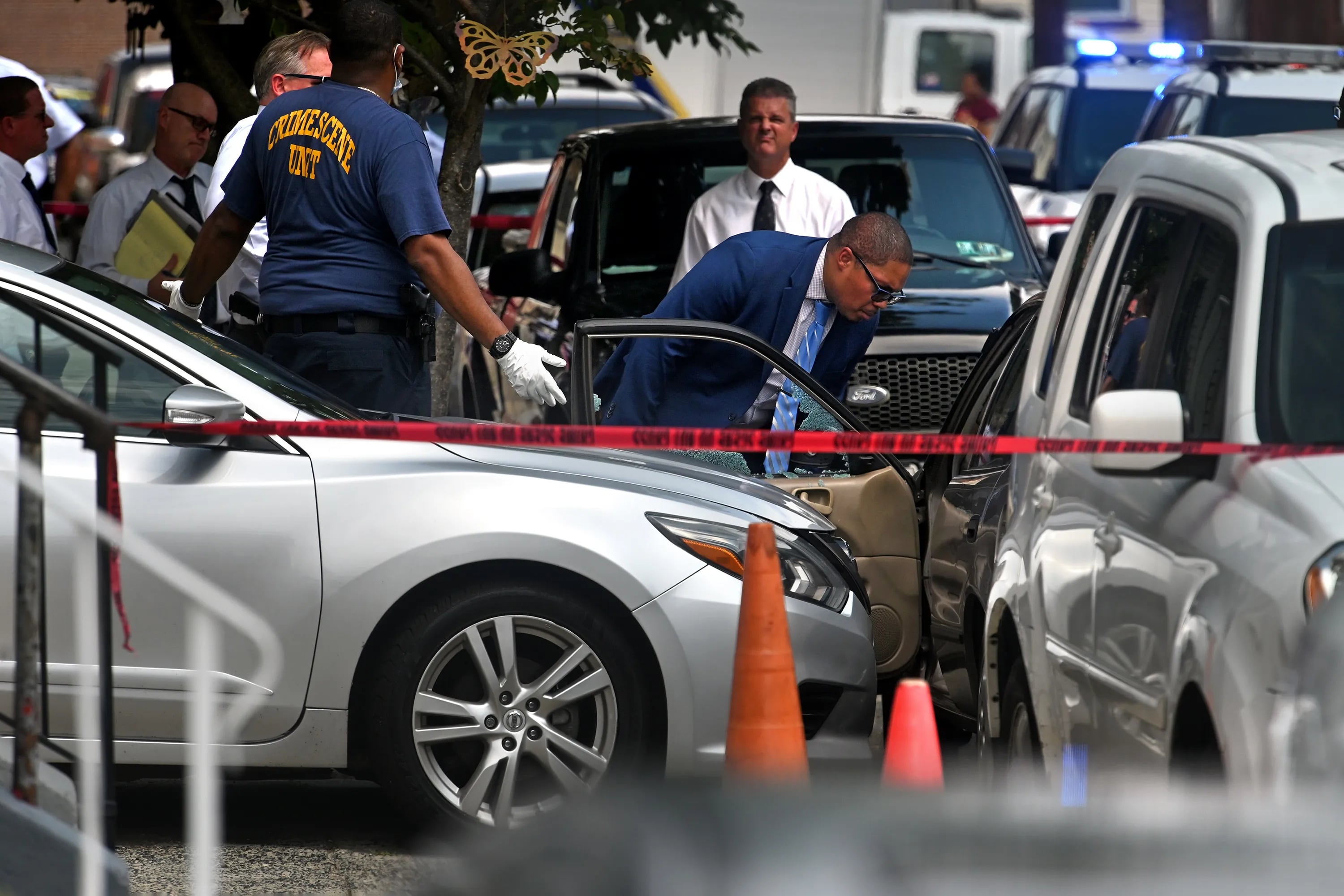 Shattered glass is visible in the drivers side window of the gold Toyota Corolla that Eddie Irizarry was driving as police investigators are on the scene in the 100 block of East Willard Street on Aug. 14. Contrary to initial statements by the police, commissioner Danielle Outlaw later said Irizarry was in his car when he was fatally shot.