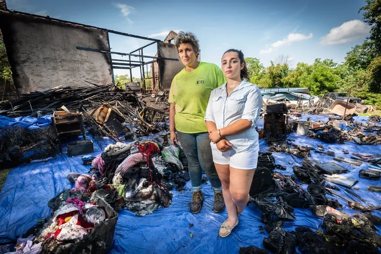 Ashley May and her daughter Sophia Nelson, right, are surrounded by their charred belongings. The barn on the property that May and her family moved into two weeks ago was heavily damaged in a fire Saturday morning.